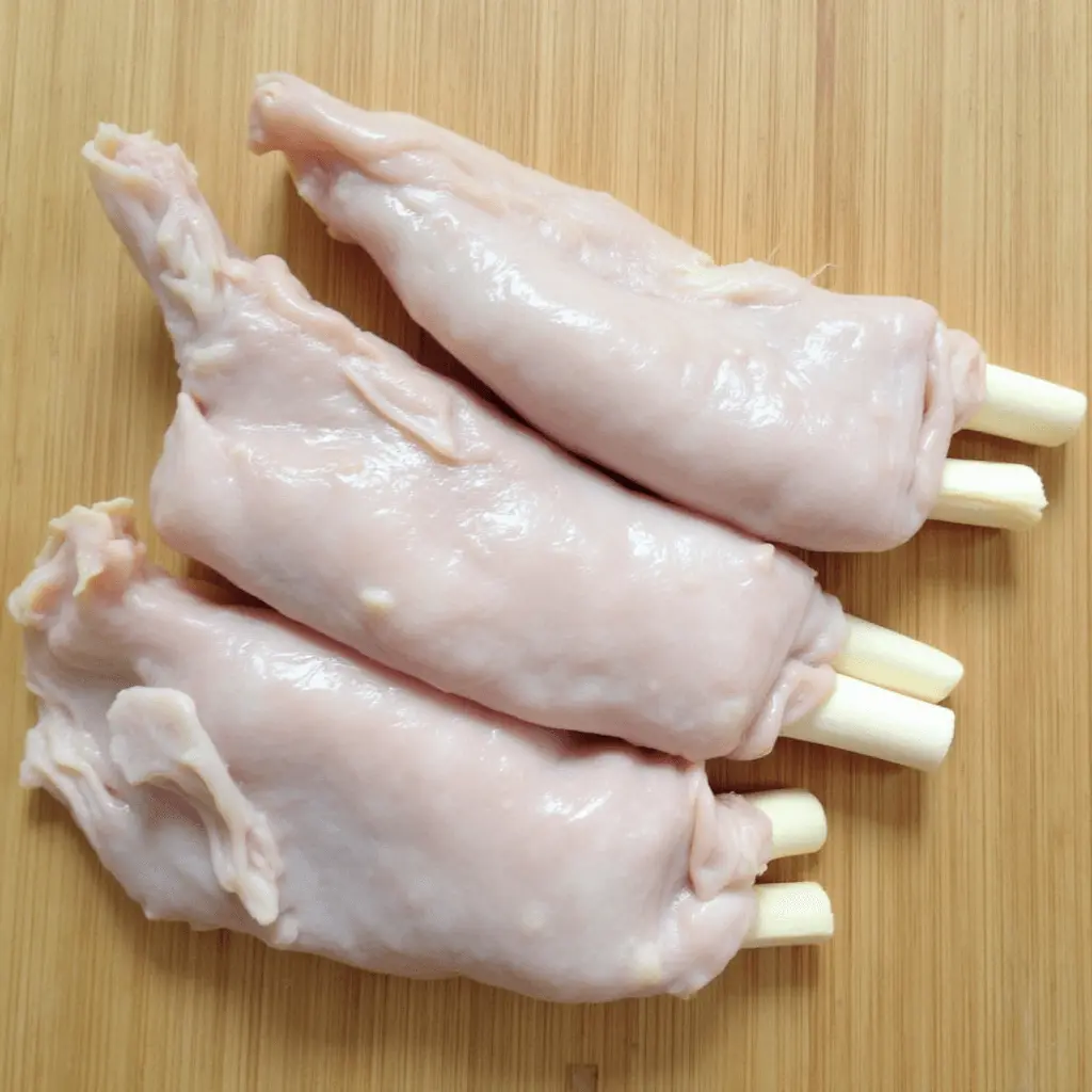 Raw beef tendons with white cartilage ends placed on a wooden cutting board.