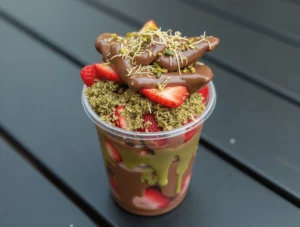 Close-up of fresh strawberries being dipped in melted chocolate.